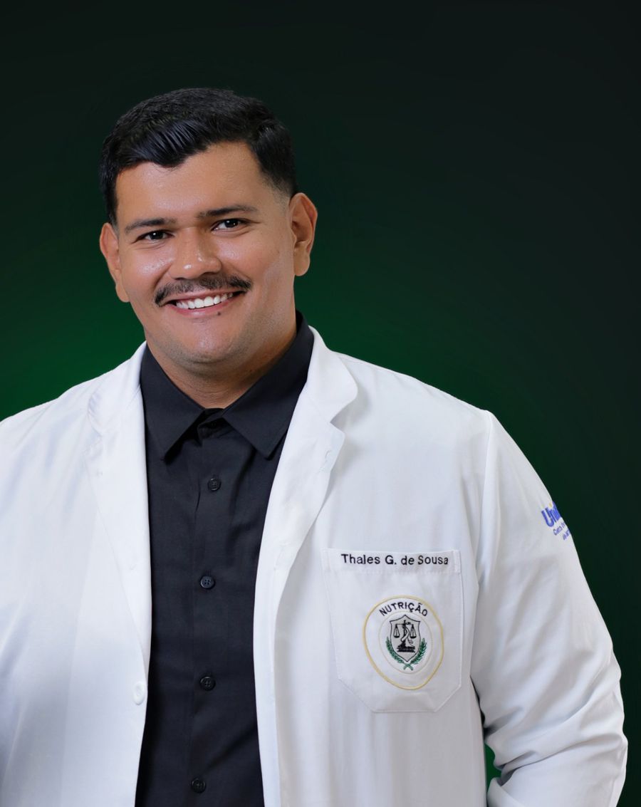 Thales sorrindo, de jaleco branco com o bordado da Nutrição no bolso